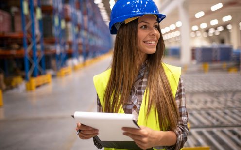 Warehouse inventory manager holding checklist and looking aside.